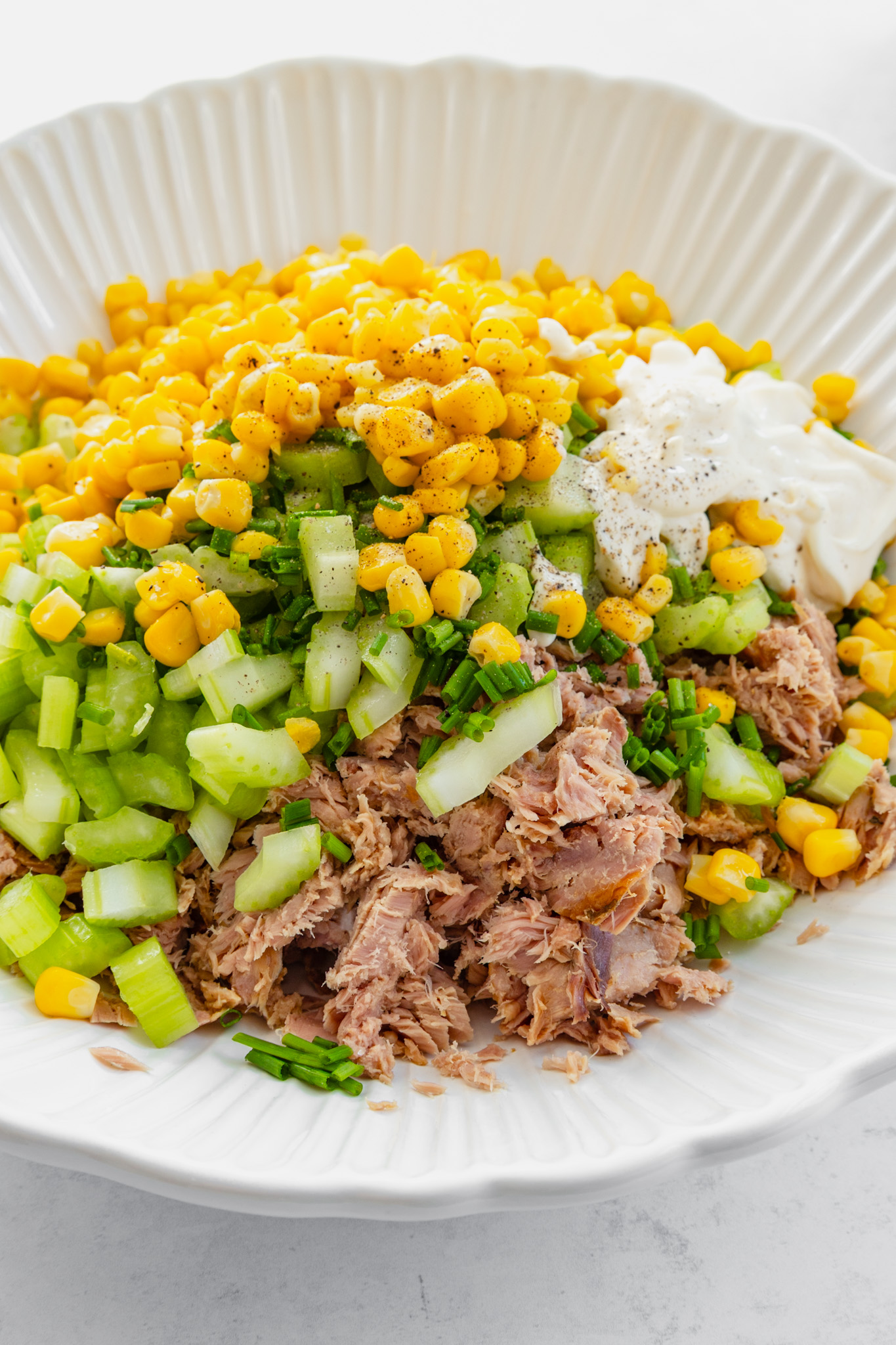 Bowl with sweetcorn mayonnaise, celery, chopped chives, and tuna