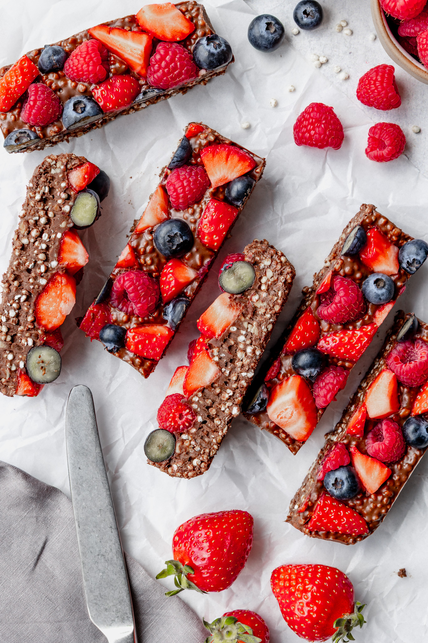 sliced berry chocolate bars with fresh strawberries, raspberries, blueberries, peanut butter and puffed quinoa or puffed rice